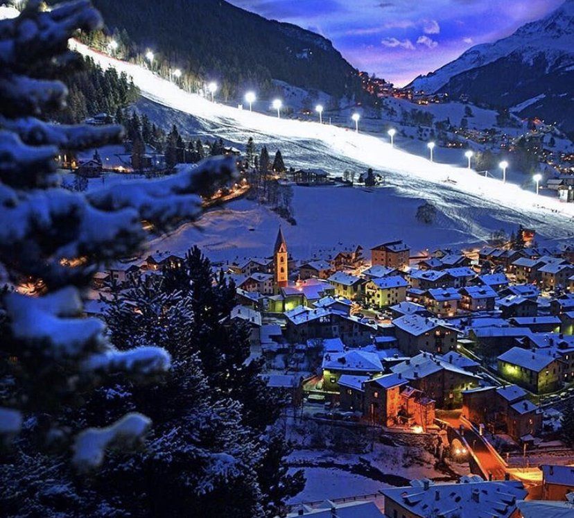 Una cittadina innevata con una pista da sci sullo sfondo