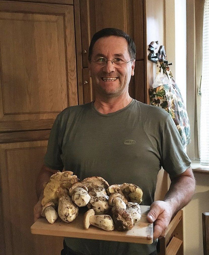 Un uomo con una camicia verde tiene in mano un vassoio di funghi