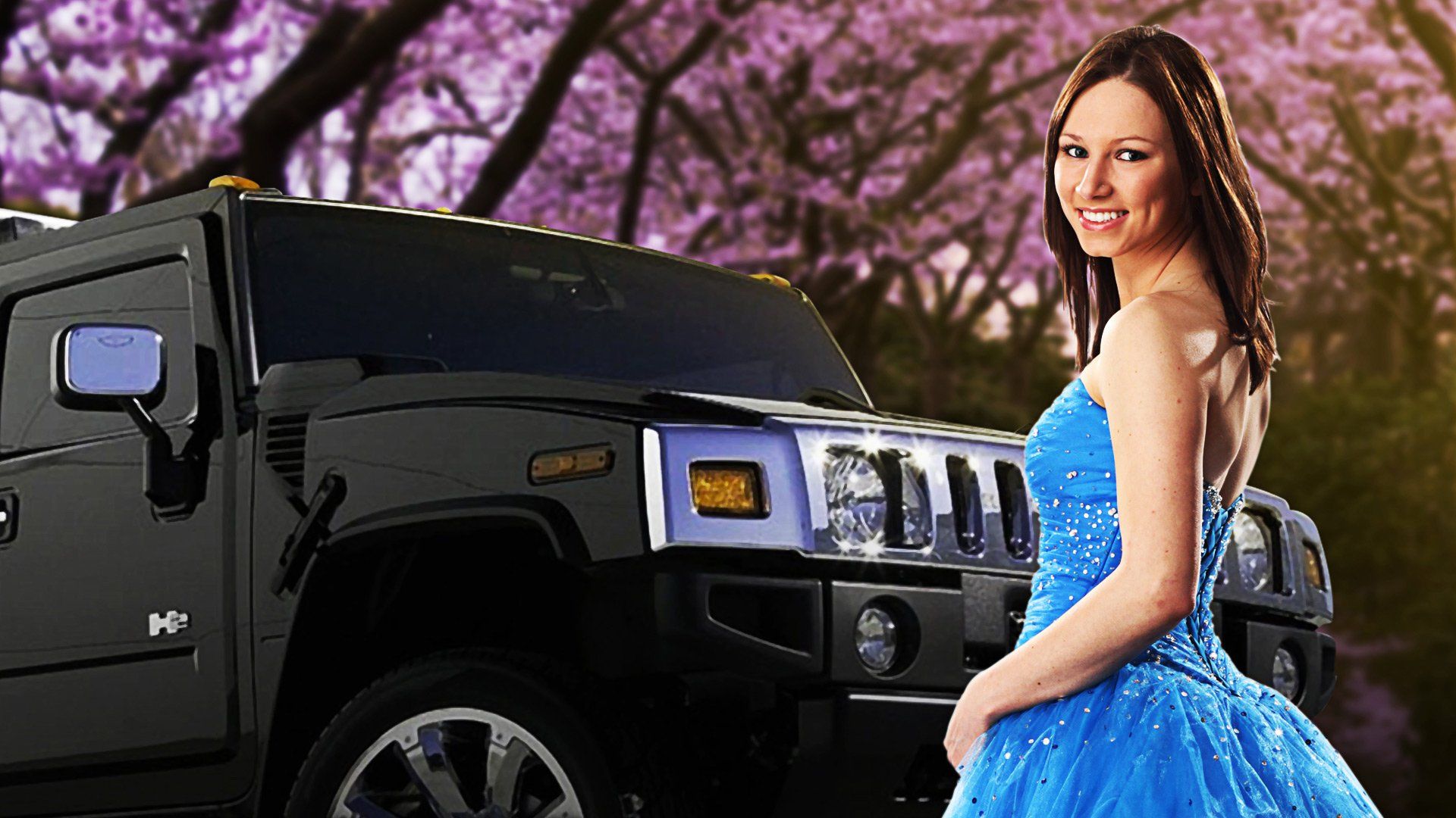 Mujer con vestido azul de pie junto a un SUV de lujo negro bajo árboles de color rosa en flor.