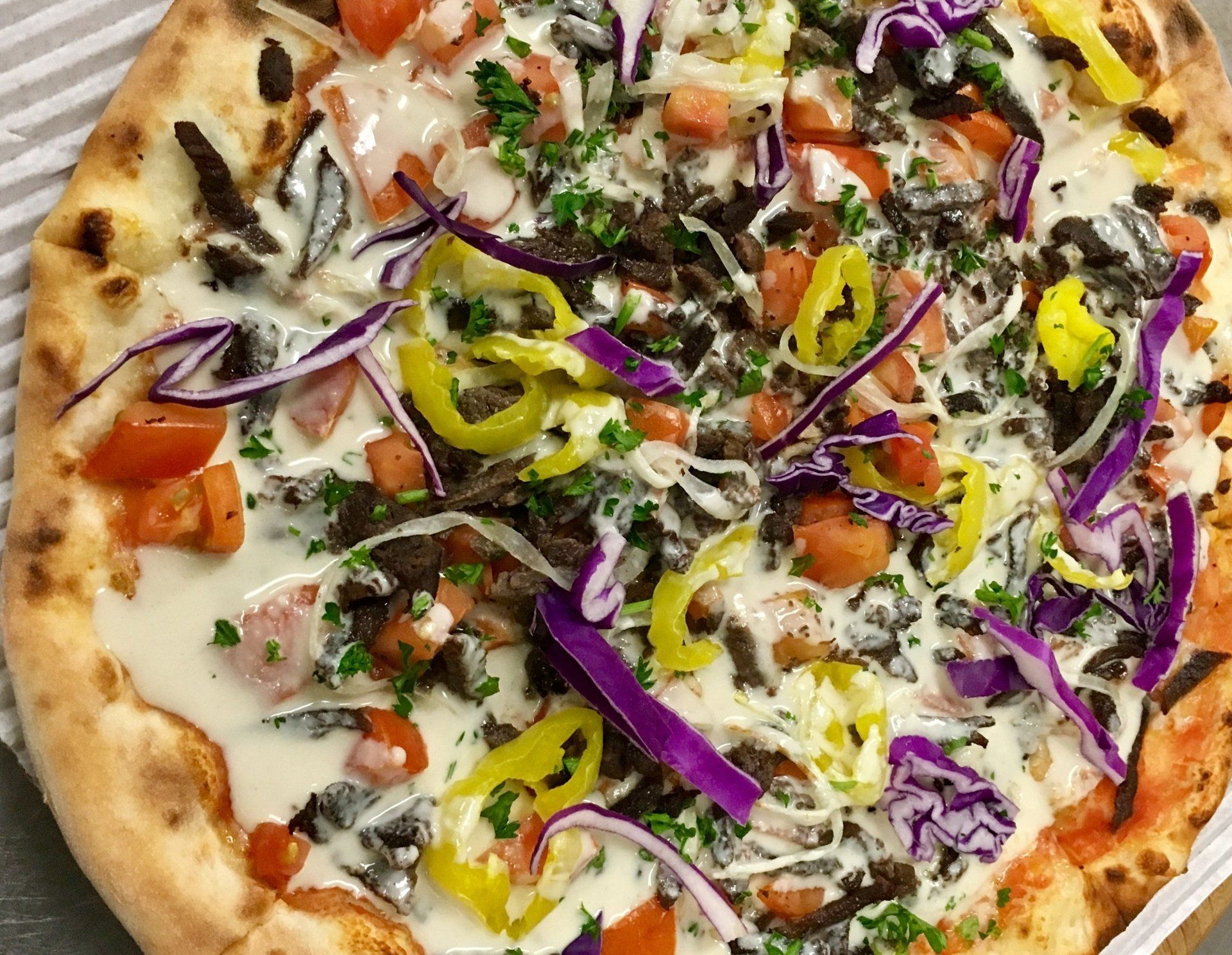 A pizza with a lot of toppings on it is sitting on a table.