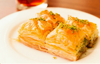 A white plate topped with a piece of baklava