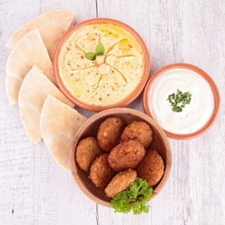 A bowl of falafel next to a bowl of hummus and pita bread.