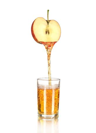 An apple is being poured into a glass of juice.