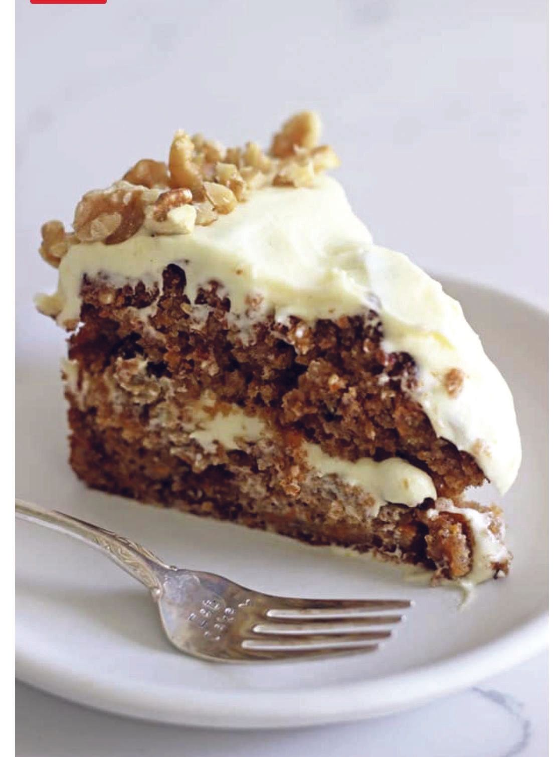 A slice of carrot cake on a white plate with a fork