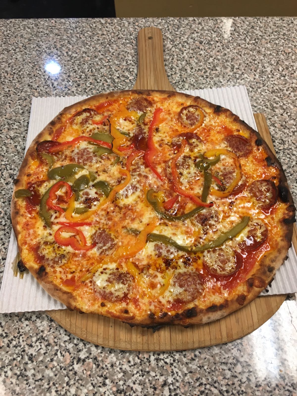 A pizza with pepperoni and cheese is on a wooden cutting board
