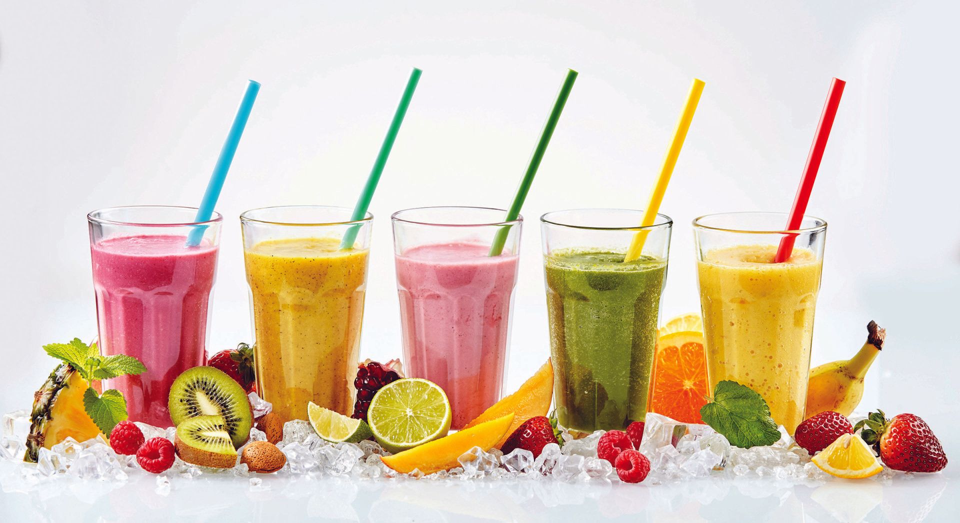 A row of smoothies with straws and fruit on ice