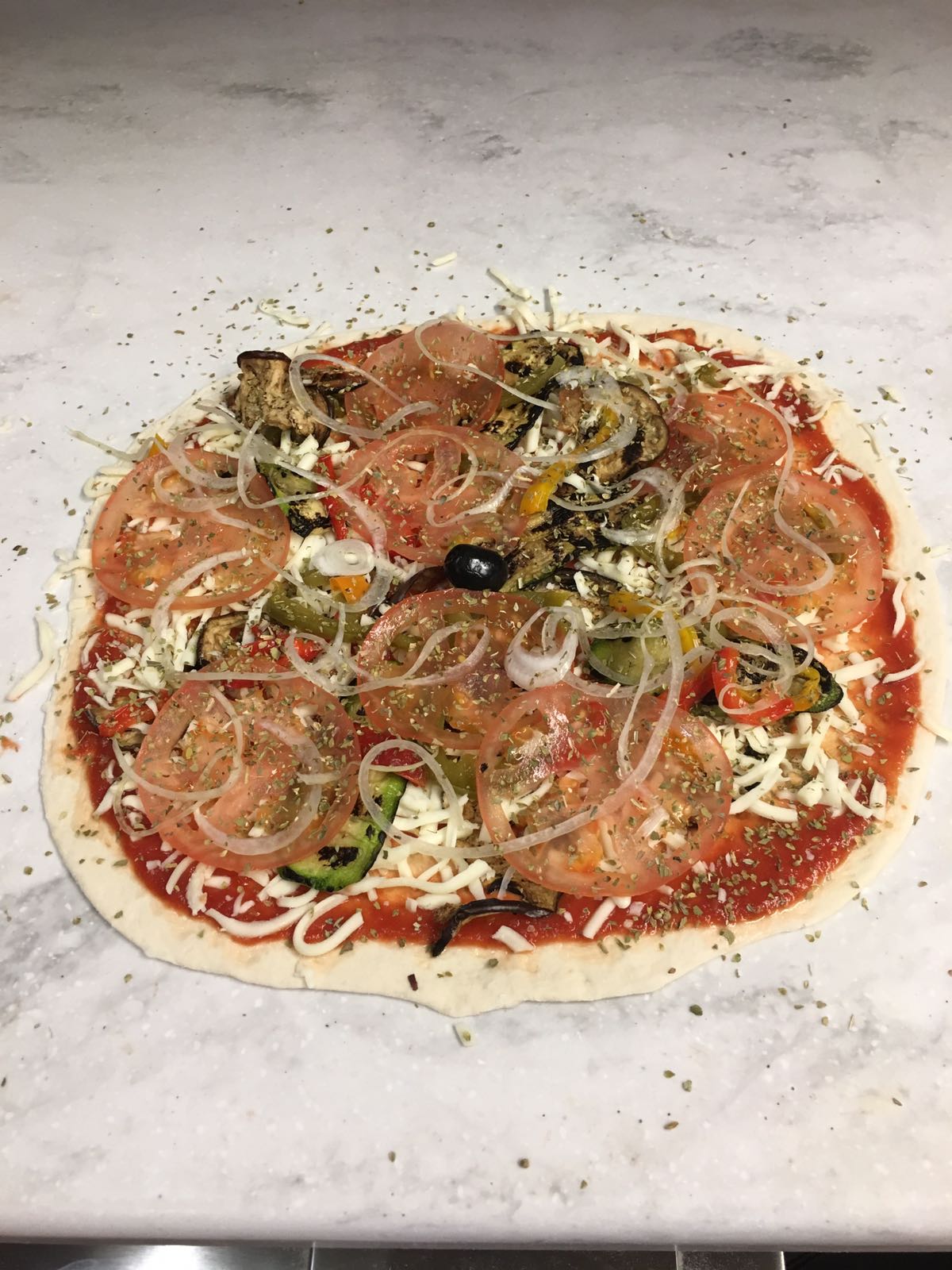 A pizza with tomatoes onions olives and cheese on a table