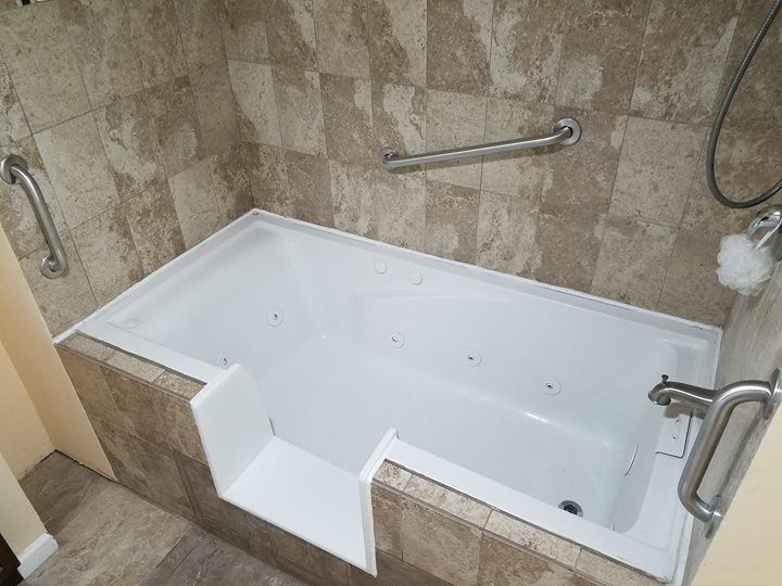 Step-in bathtub with white interior and beige tiled walls in a bathroom