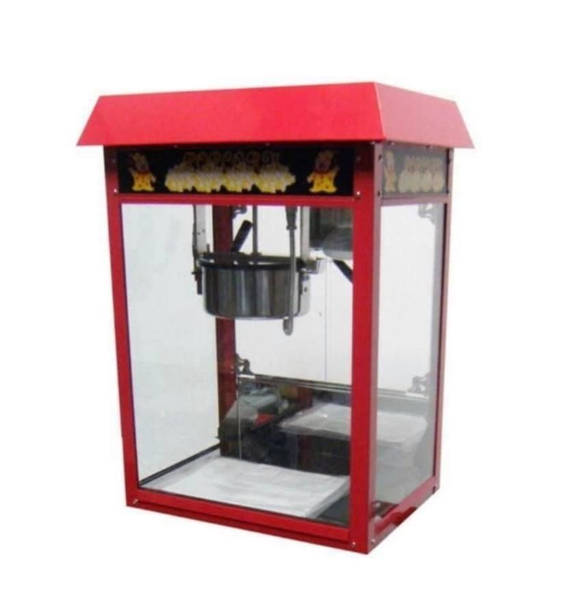 Rode popcornmachine met glazen zijkanten en een metalen ketel aan de binnenkant.