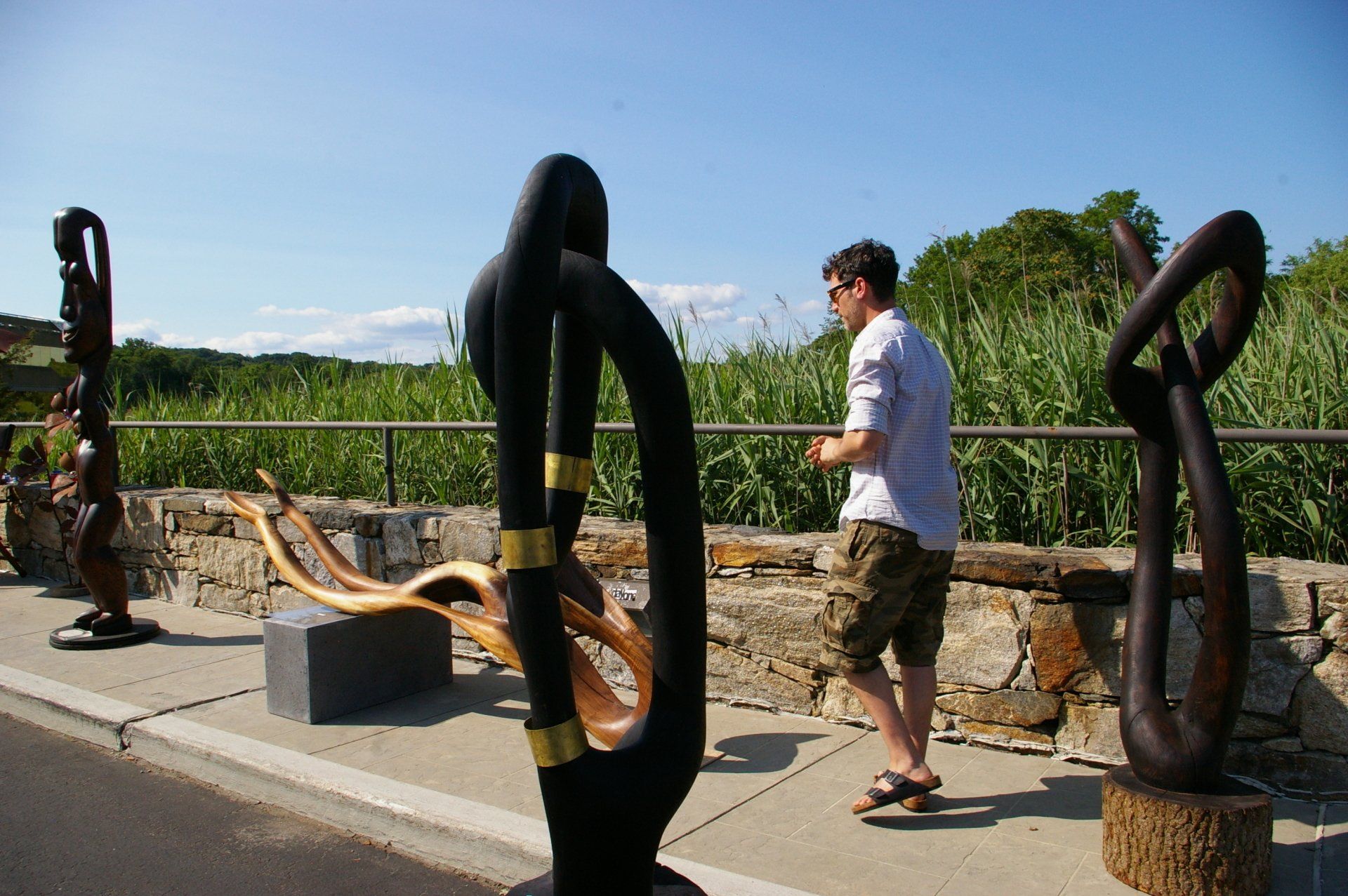 A man is standing next to a sculpture on a sidewalk
