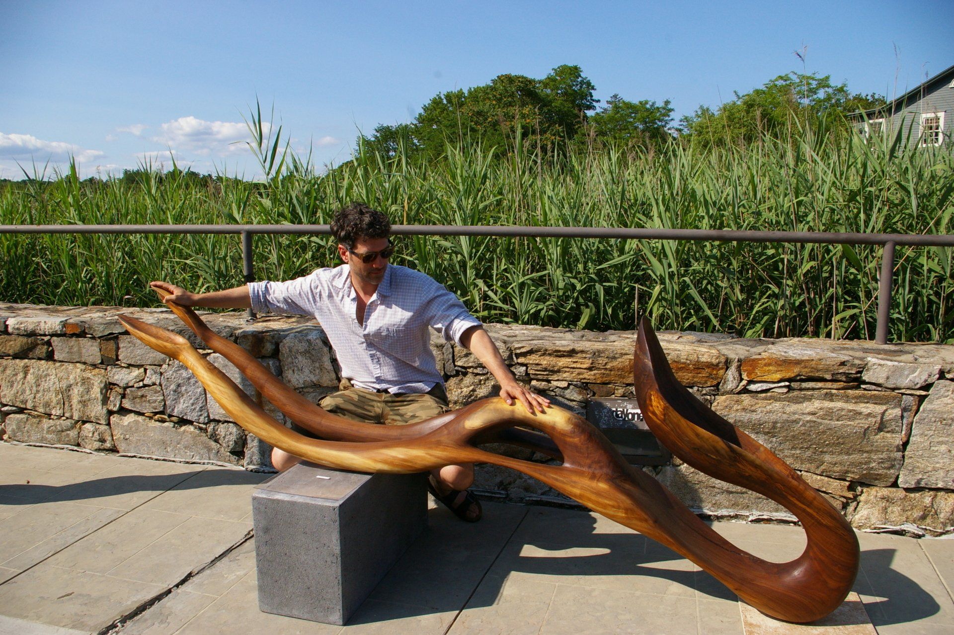 A man is sitting on a bench next to a large wooden sculpture