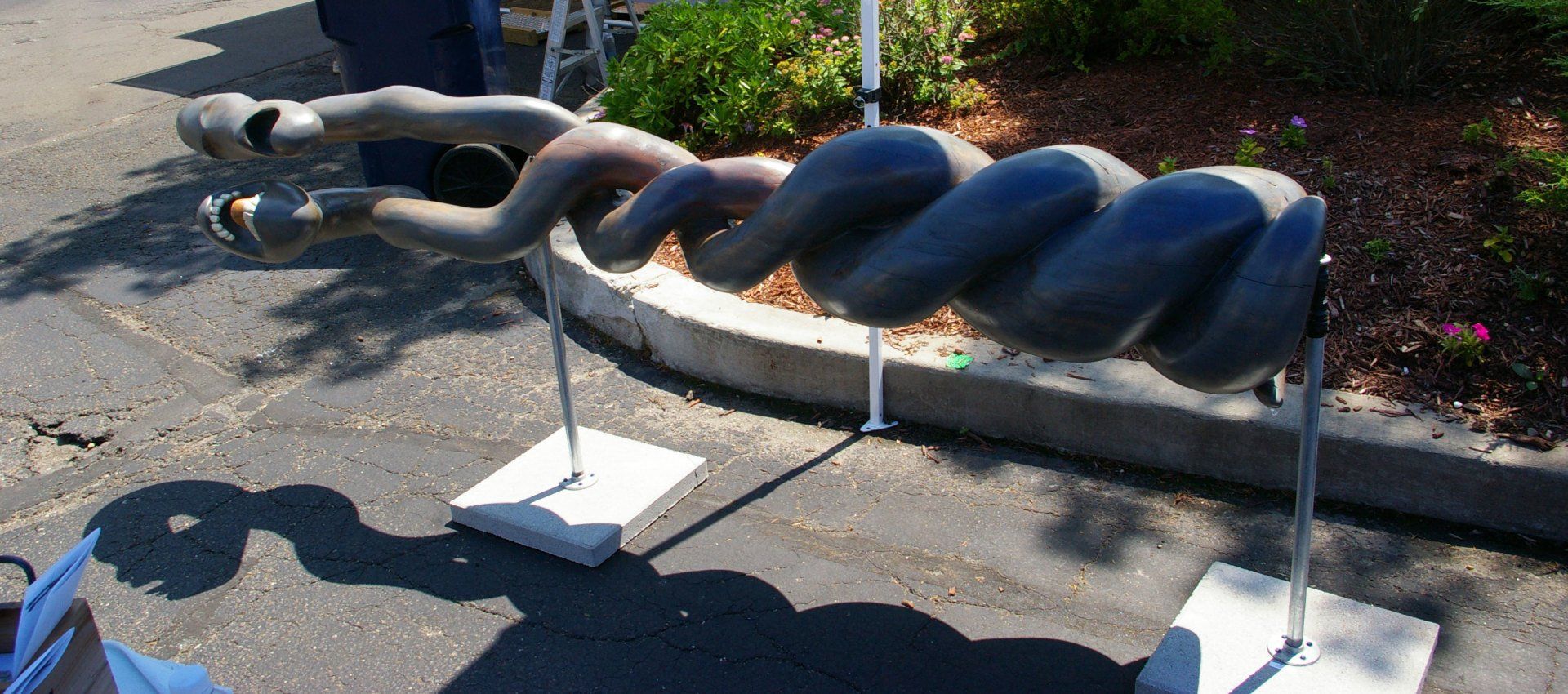 A sculpture of a snake is on display in a parking lot