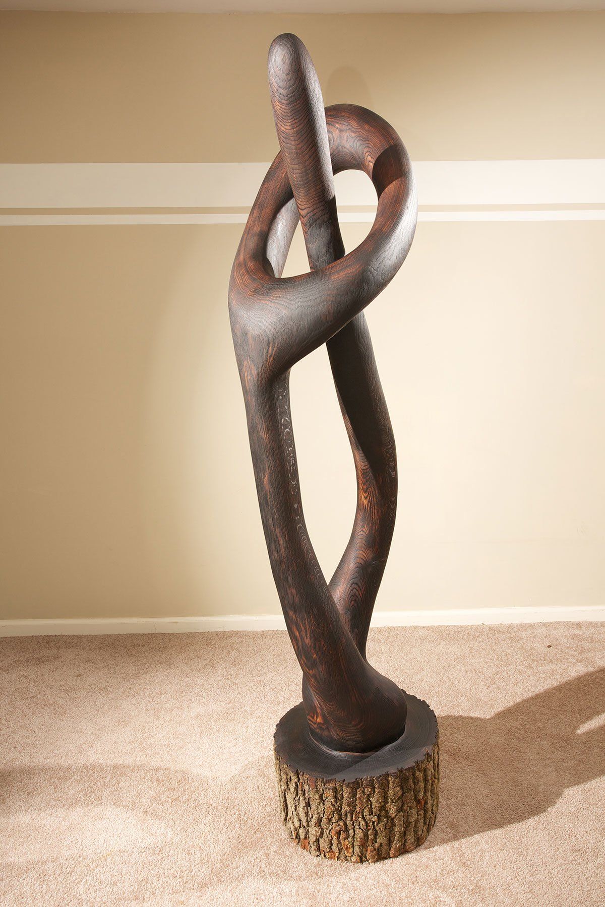A large sculpture is sitting on a wooden base in a room.