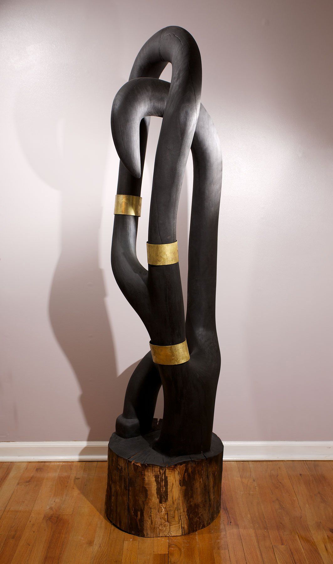 A large black sculpture is sitting on a wooden floor in a room.