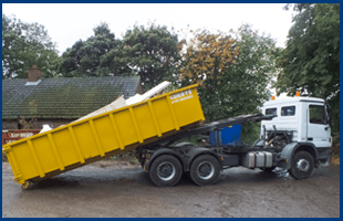 To take advantage of our same day skip hire in Tyne and Wear call 0191 584 3382 Yellow wheel in skip getting dropped off by a blue and white truck
