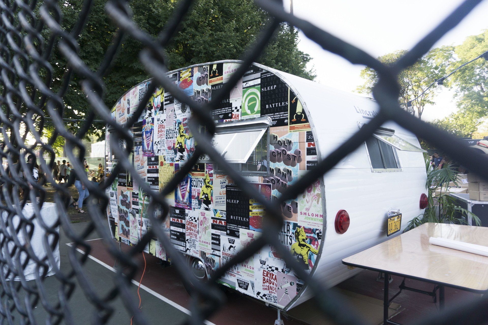 A white trailer with stickers on it is behind a chain link fence