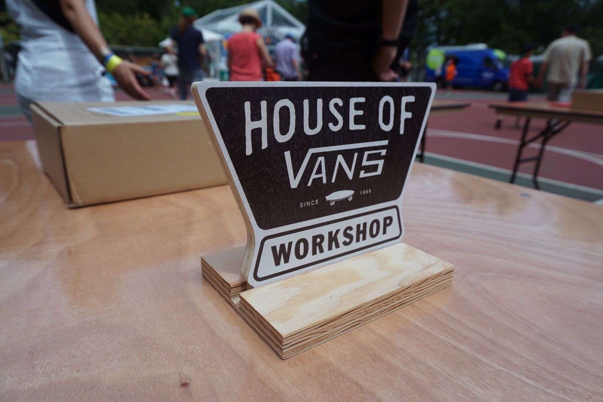A sign on a wooden table that says house of vans workshop