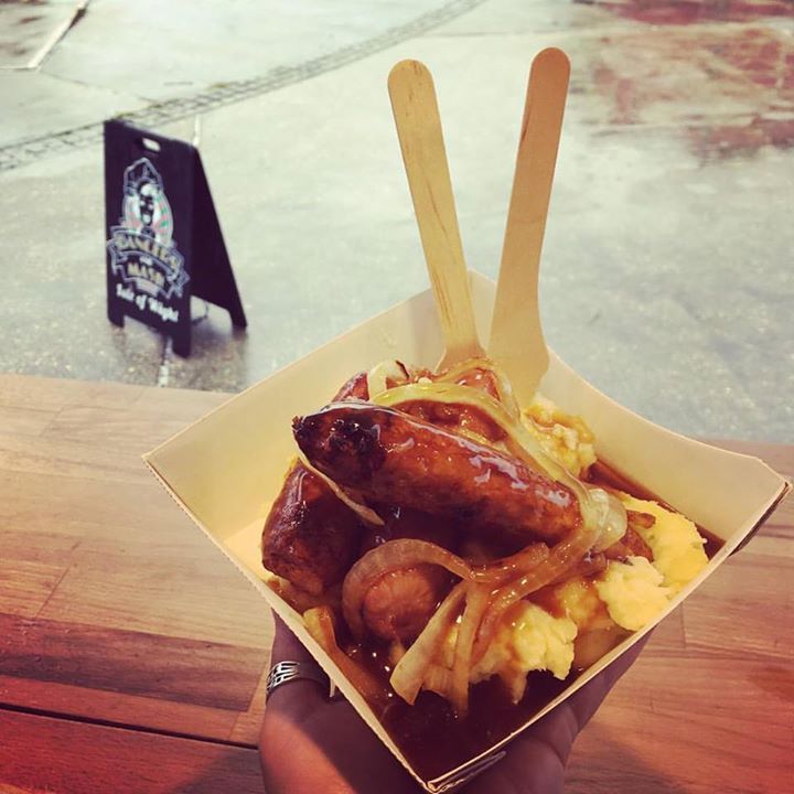 A person is holding a bowl of food with wooden spoons