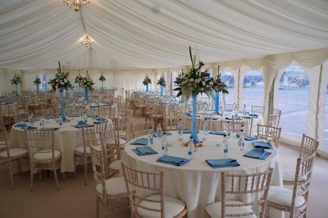 A large tent with tables and chairs set up for a wedding reception.