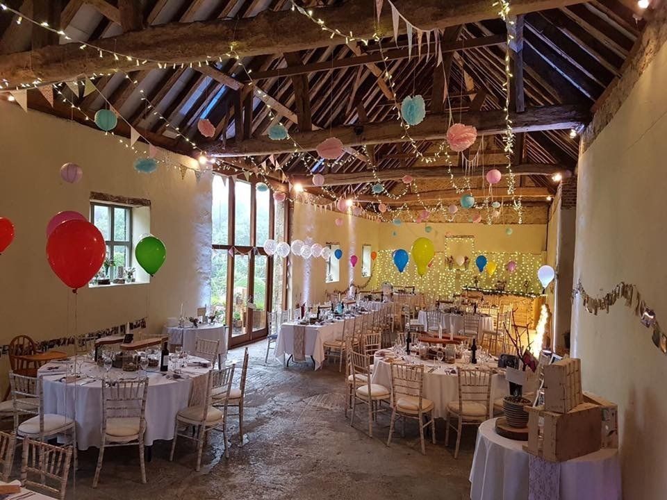 A large room with tables and chairs and balloons hanging from the ceiling.