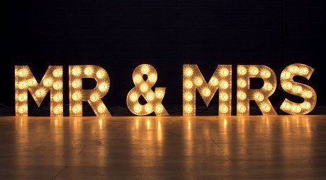 The letters mr and mrs are lit up on a wooden table.
