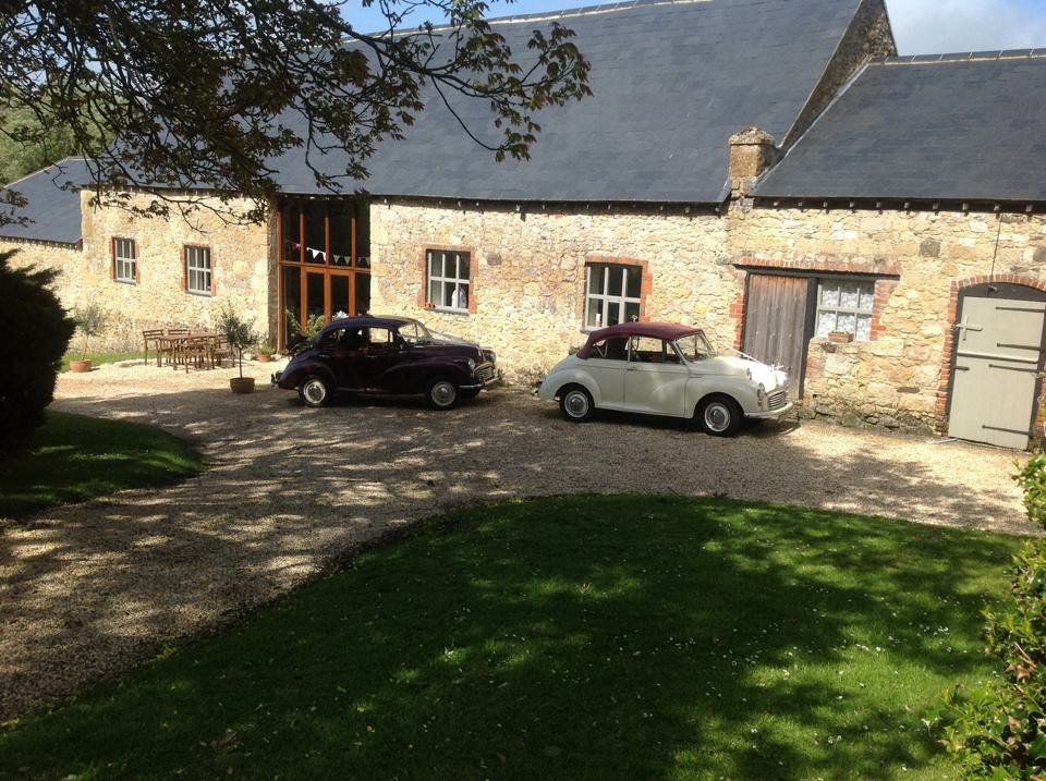 Two cars are parked in front of a stone building.