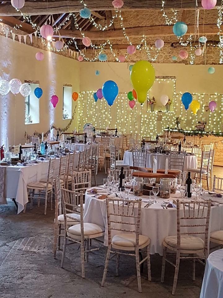 A large room with tables and chairs and balloons hanging from the ceiling.
