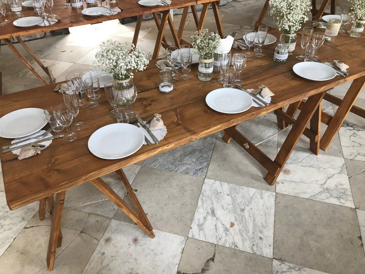 A wooden table with plates , glasses , and vases on it.