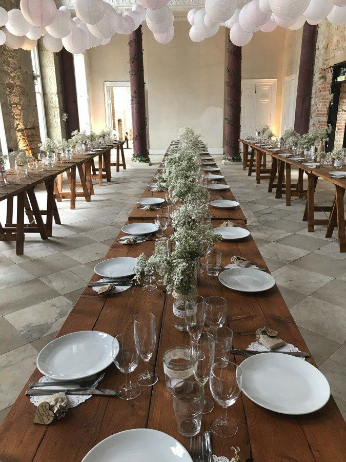 A long wooden table with plates , glasses , and flowers on it.