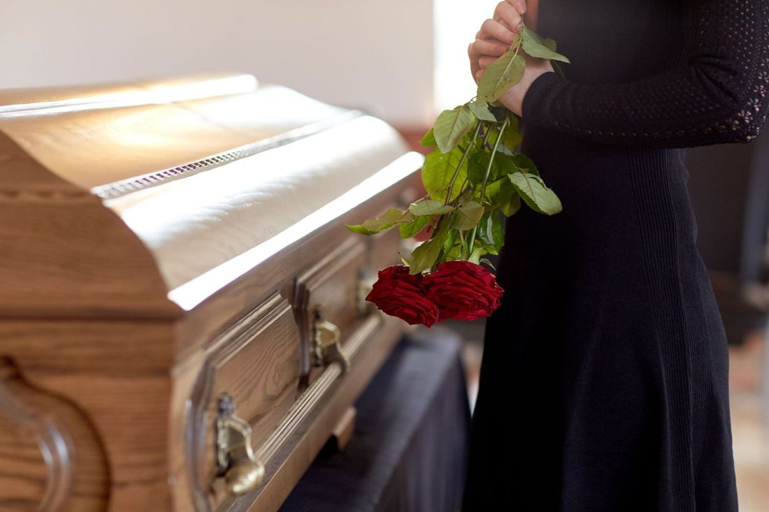 Una donna che porge omaggio alla bara di un defunto
