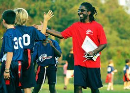 A man in a red shirt is giving a high five to a group of soccer players.