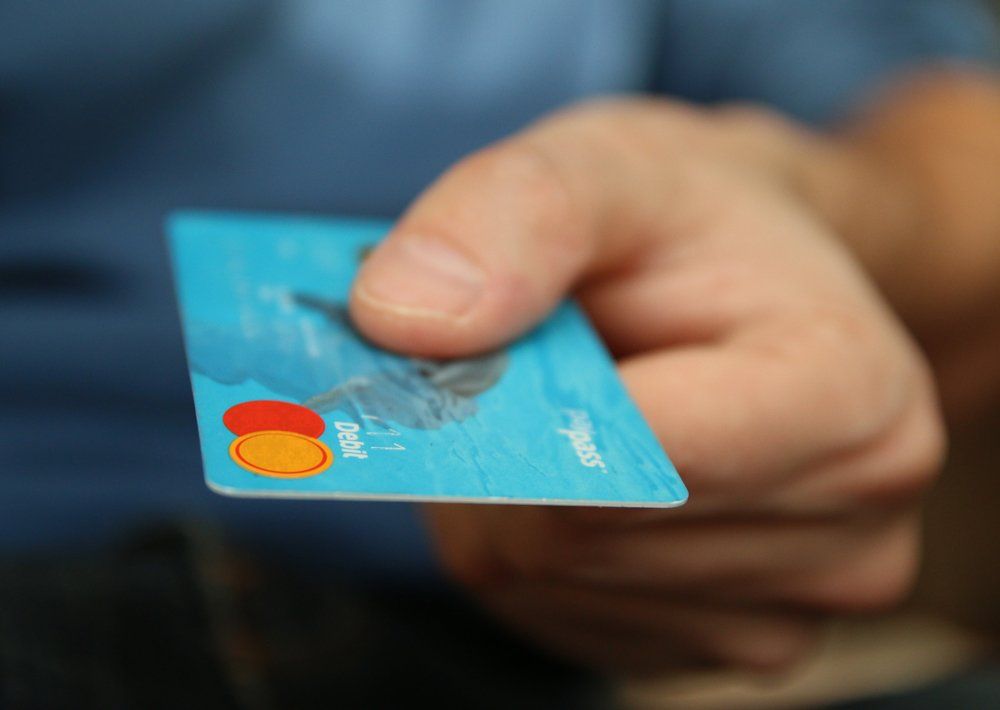 A person is holding a blue credit card in their hand.