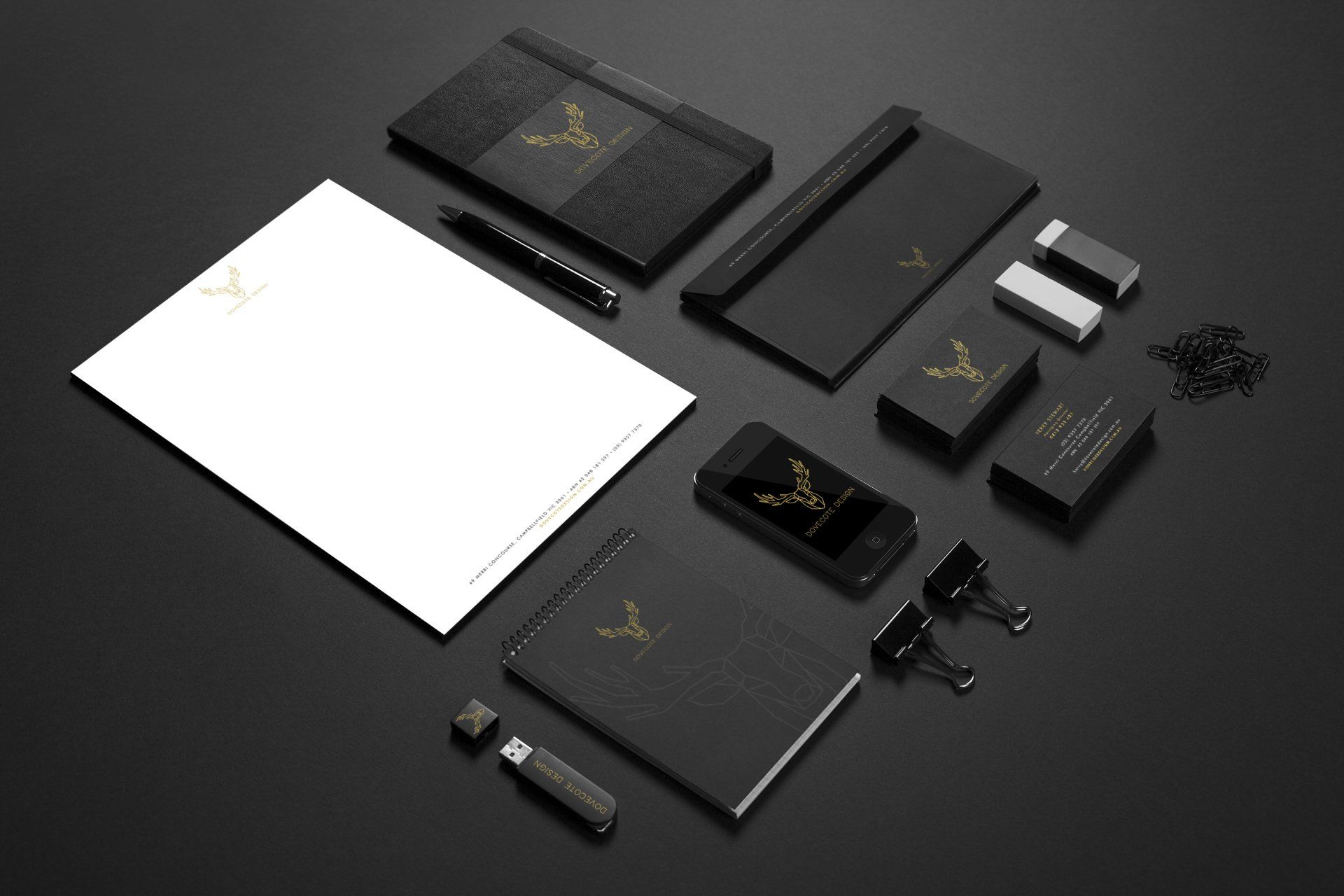 Black office supplies with gold accents, including stationery, phone, and a pen.