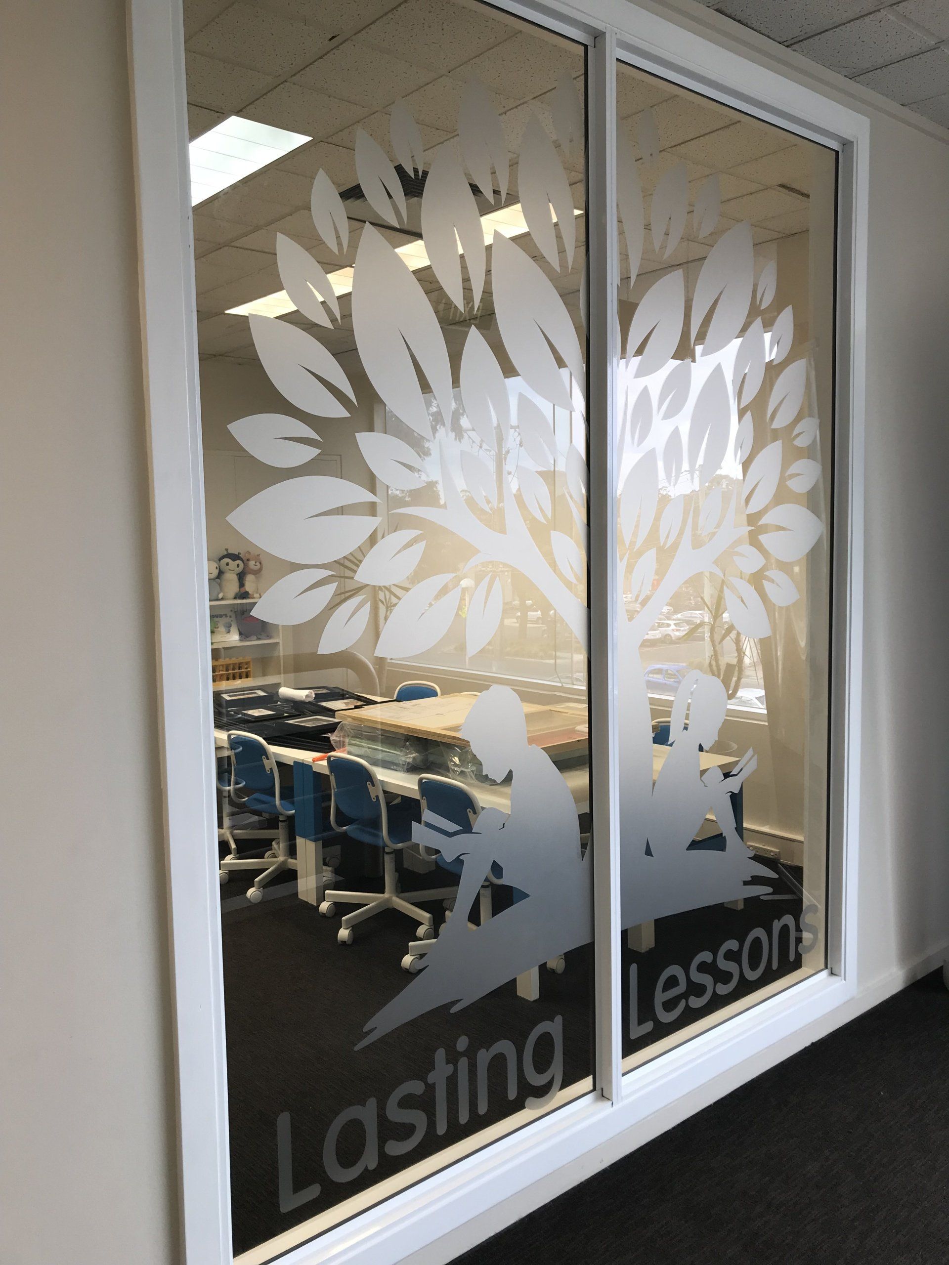 Office door with frosted glass leaf design and the words “Lasting Lessons” above a conference room