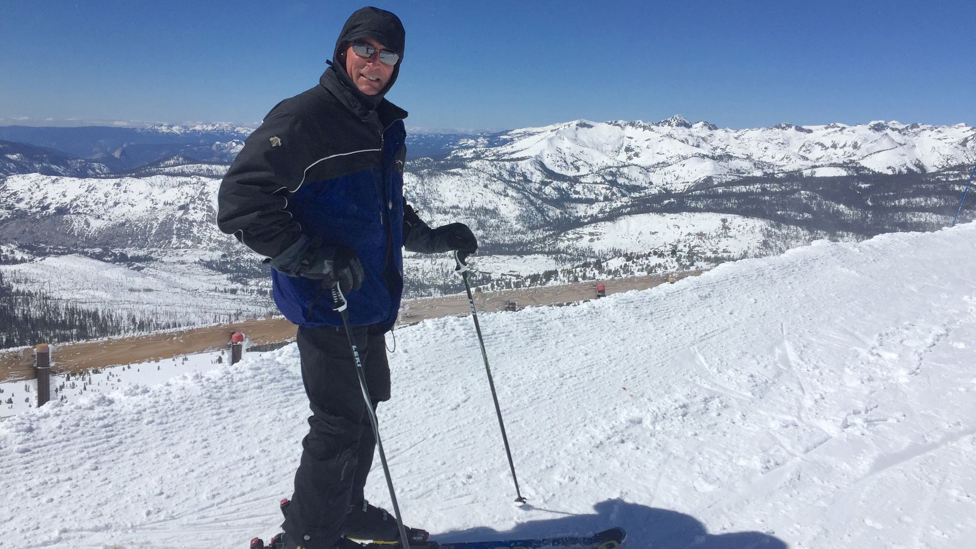 A man is standing on skis on top of a snow covered mountain.