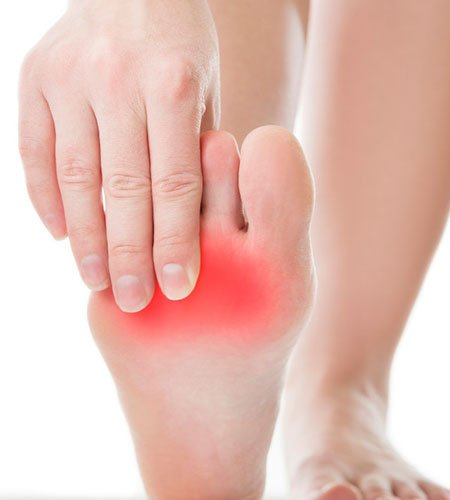 A person is holding their foot in pain.