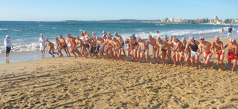 A group of people are running on a beach near the ocean.