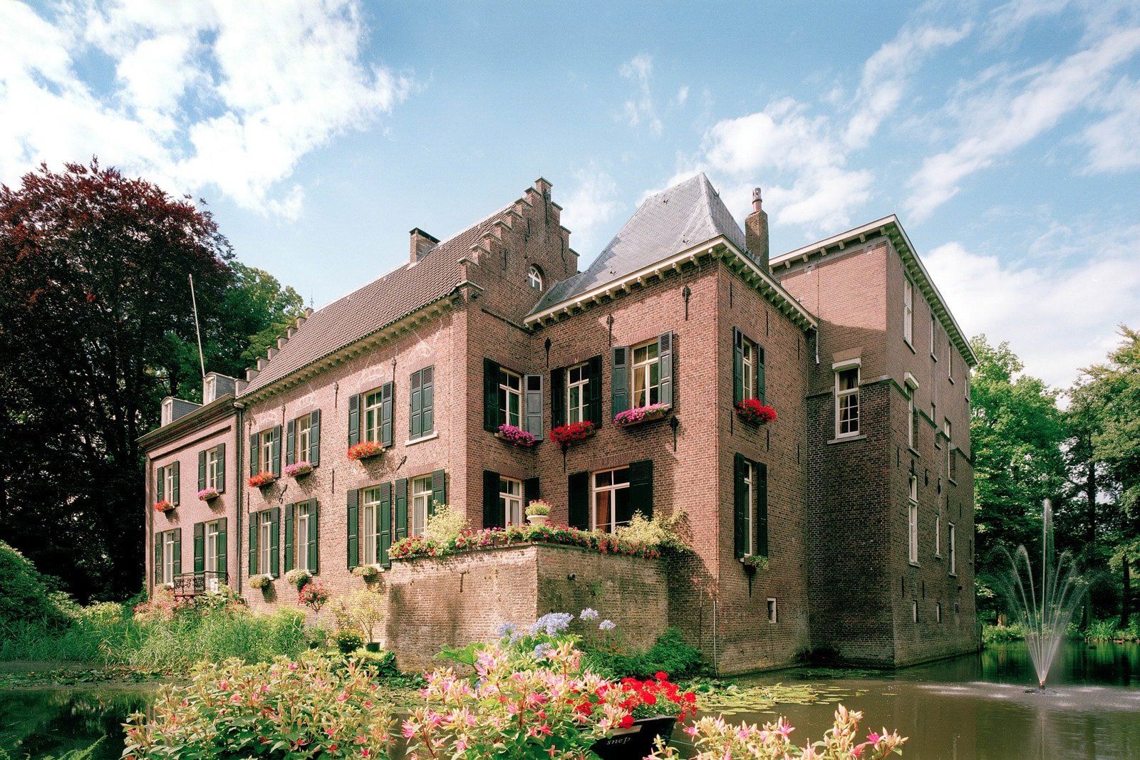 Een groot bakstenen gebouw met een vijver ervoor