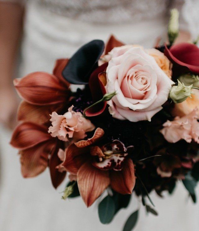 Een vrouw in een witte jurk houdt een boeket bloemen vast