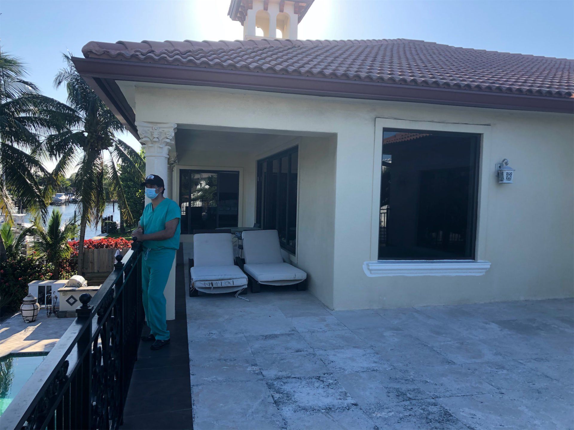 a woman wearing a mask is standing on a balcony in front of a house .