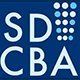 SDCBA logo in white on dark blue, with a 3x4 grid of light blue dots on the right
