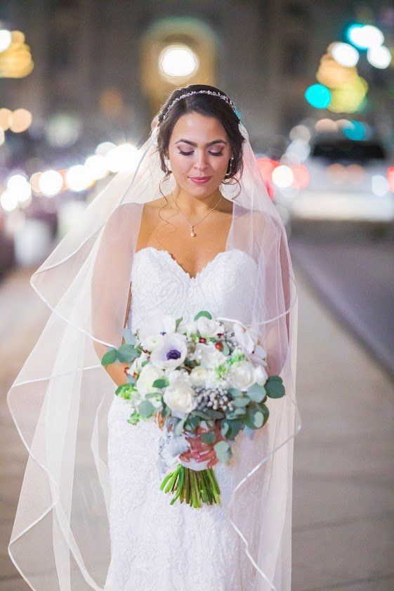 The bride is wearing a veil and holding a bouquet of flowers.