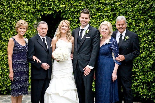 A bride and groom are posing for a picture with their parents
