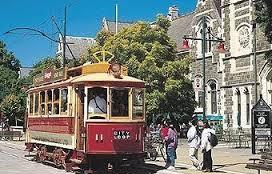 A trolley is driving down a street in front of a church.