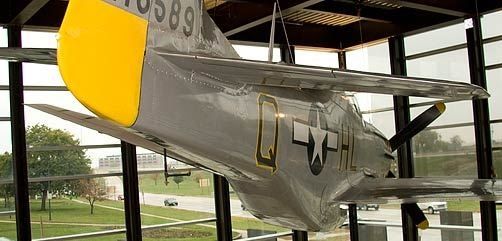 Yellow-and-silver vintage airplane inside a hangar, shown in side view.