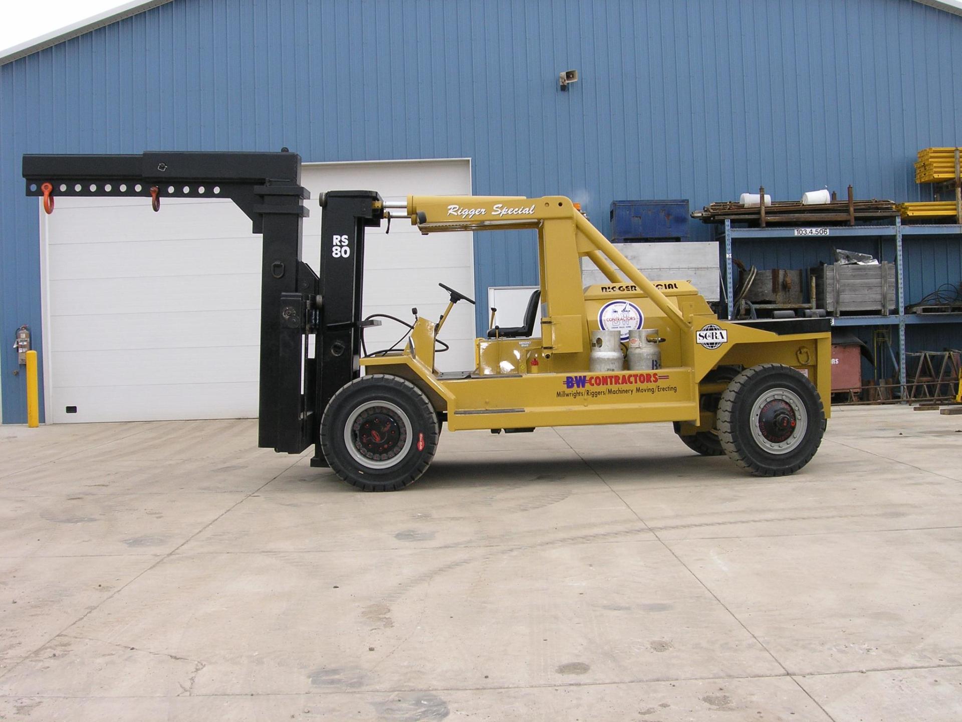 Yellow forklift parked on concrete beside a blue warehouse wall and white garage door