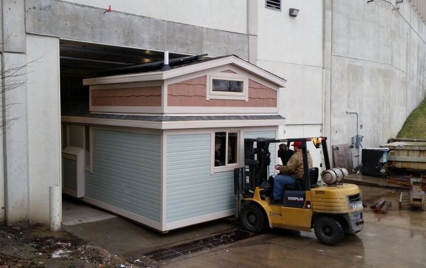 Forklift moving a small house under a bridge opening