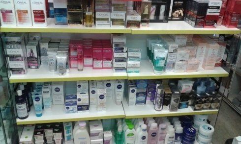 Scaffali pieni di vari prodotti cosmetici e per la cura della pelle in un ambiente di vendita al dettaglio.