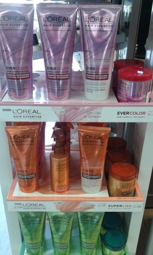 Espositore di prodotti per la cura dei capelli L'Oréal in tubetti rosa, arancioni e verdi e barattoli coordinati.