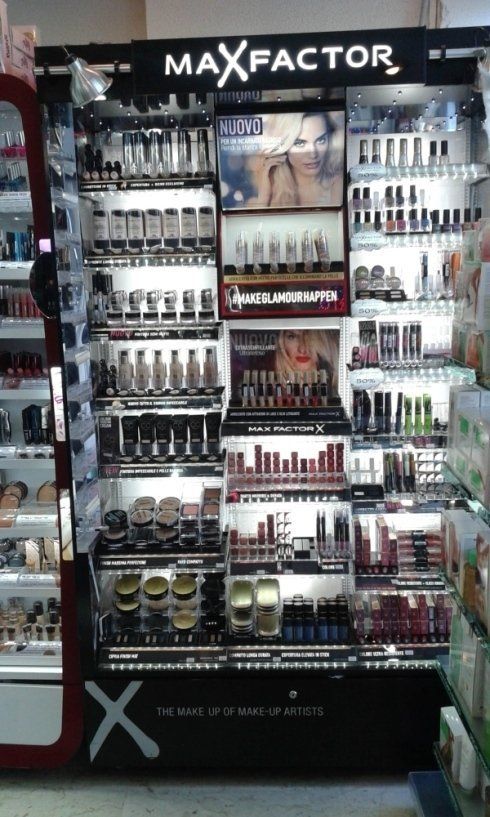 Espositore per trucchi Max Factor in un negozio, che espone vari prodotti cosmetici sotto una luce intensa.